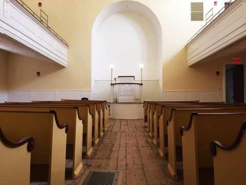 Wooden benches facing a raised platform; African Meeting House at Boston African American National Historic Site
