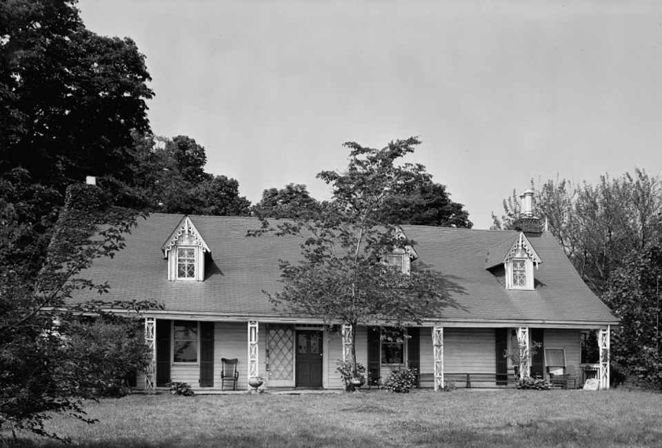 Black and white photo of a two-story house with a small garden out front