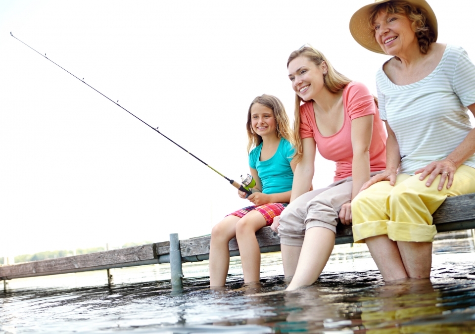 Three generations of family sit on a dock, fishing