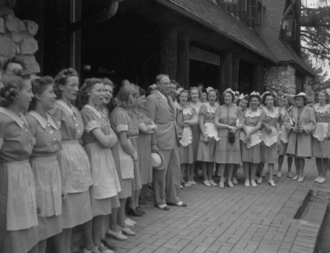 A vintage photograph of a group of employees singing to Governor Raymond E. Baldwin