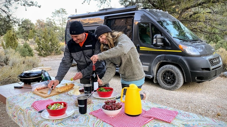 Two campers enjoy a picnic set up on a table next to their Winnebago in Great Basin National Park