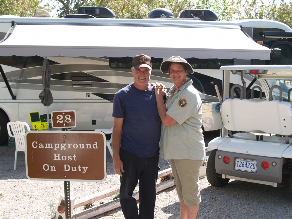 Volunteer campground hosts pose for a photograph in a campground parking lot