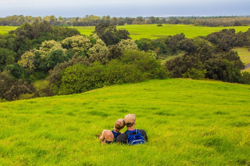 Two hikers rest on a grassy hill