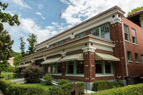 Exterior of Superior Bathhouse, a brick building with green-paneled windows and striped green and yellowawnings