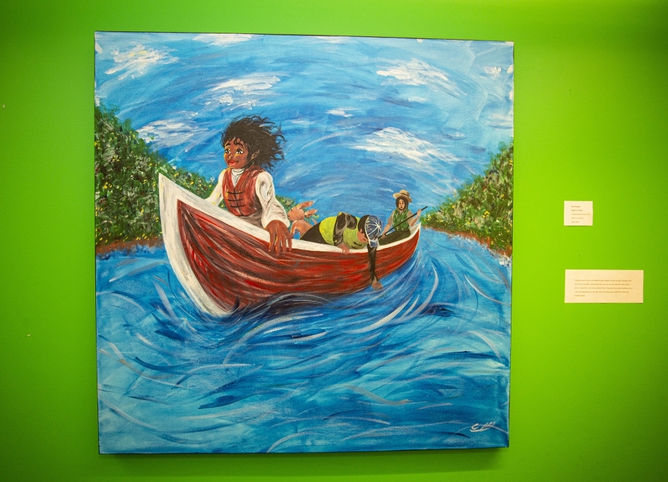 Painting against a bright green wall, depicting a young woman riding in a canoe down a river, wind blowing in her hair.