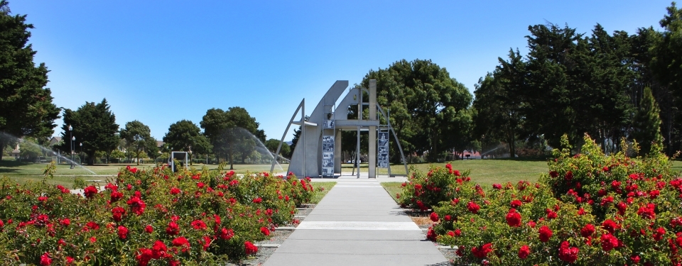 The architecturally modern outdoor memorial surrounded by red flowers and greenery at Rosie the Riveter WWII Home Front National Historical Park.