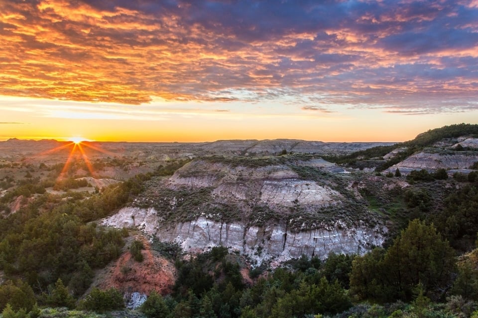 A golden sunset over the rolling bluffs of the badlands at Theodore Roosevelt National Park