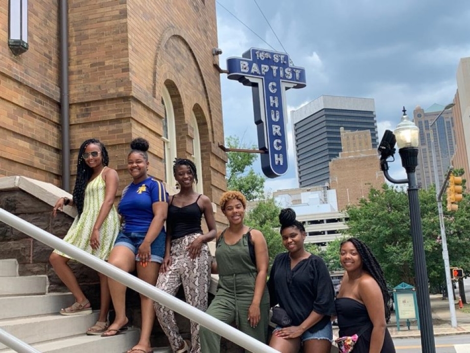 A group of young women stand on the steps of 16th Street Baptist Church