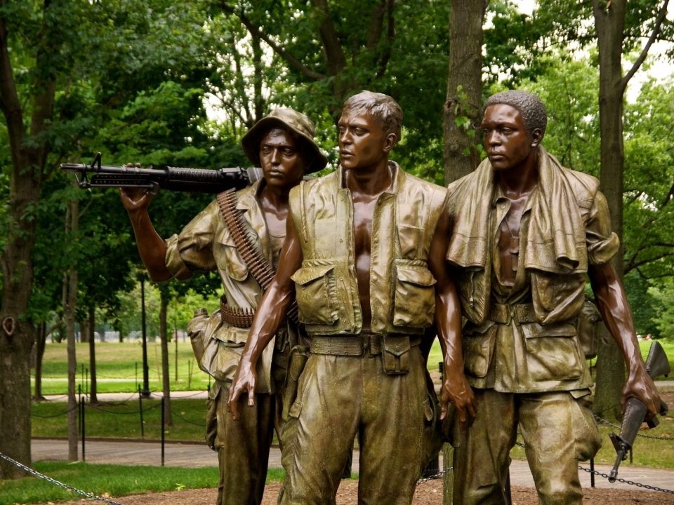 A statue of three Vietnam War soldiers gazing toward the Memorial Wall.