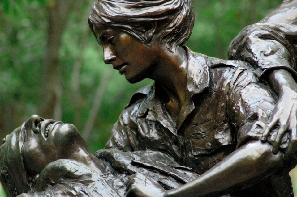 Close up a bronze statue in which a woman cradles a fallen soldier