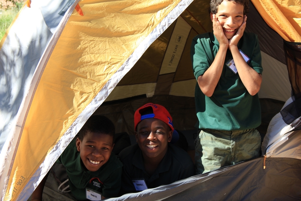 Three young park visitors pose in a tent