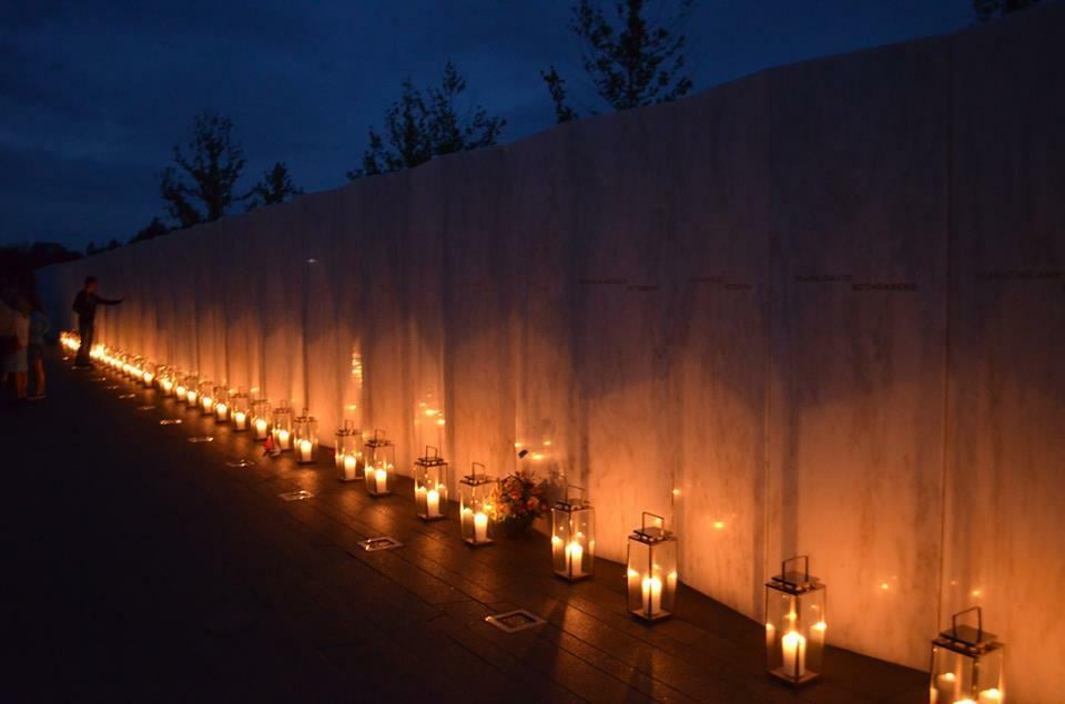 Luminaria lined up against a stone wall at night